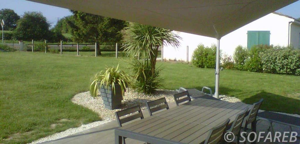 Grande voile d-ombrage qui abrite la terrasse et la table à manger d-une maison