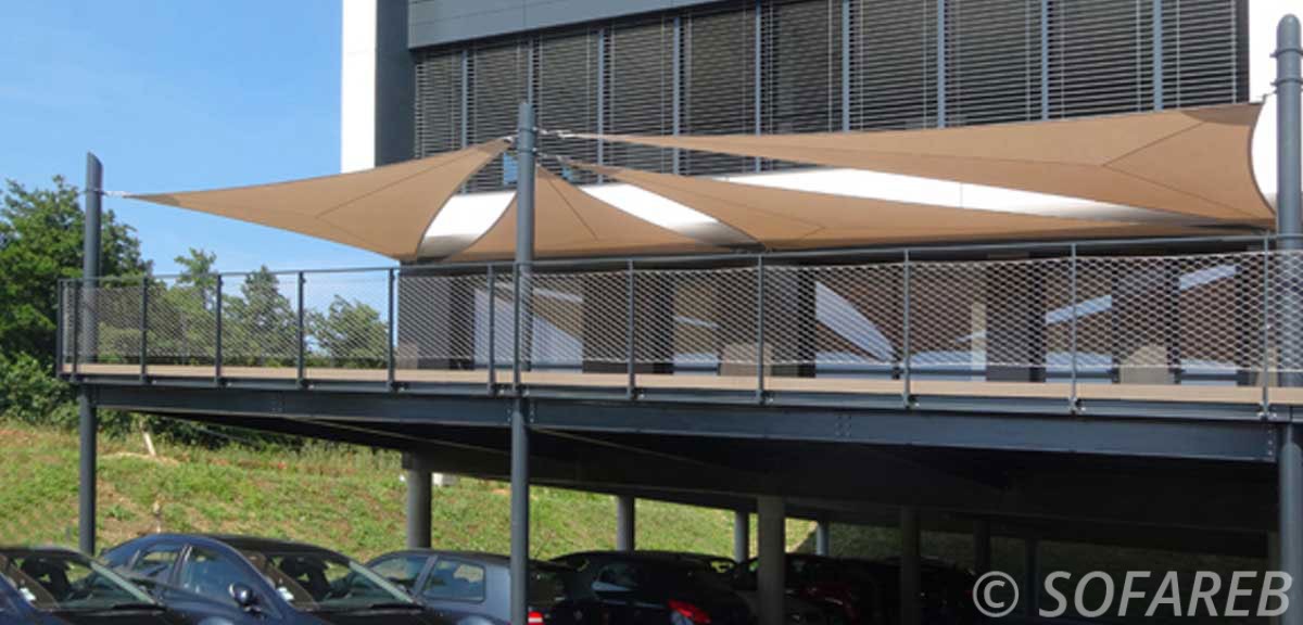 Voiles dombrage triangulaires grand format installée au dessus du balcon dun immeuble