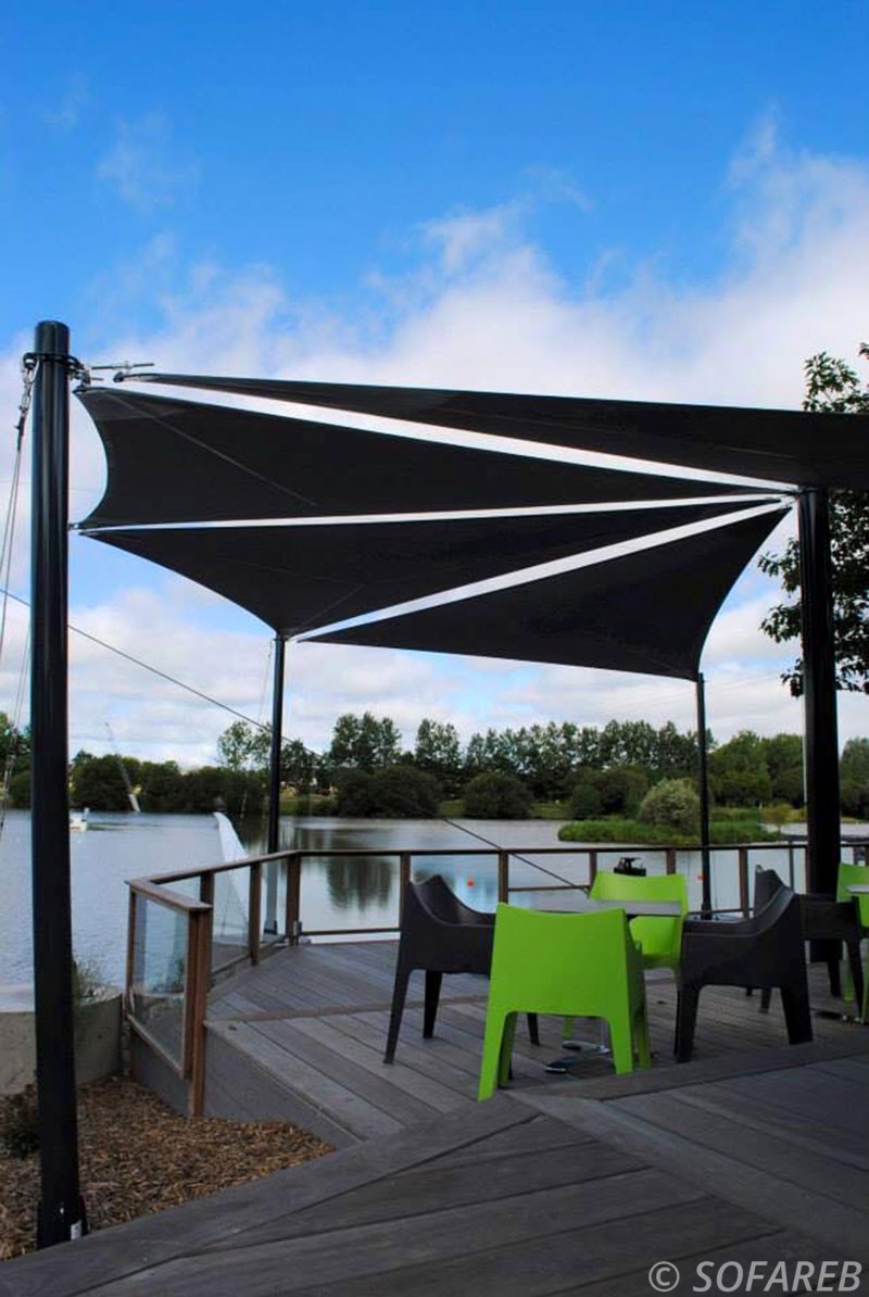 Voiles d'ombrage noires fabriquées par Sofareb pour la terrasse d'un restaurant près d'un lac en Vendée