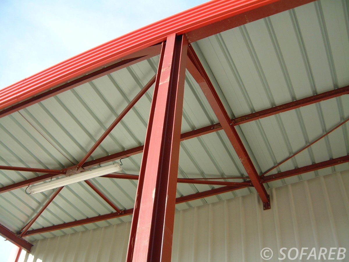 pergola professionnel en métal rouge et blanche adossé à un bâtiment en métal style an-gare