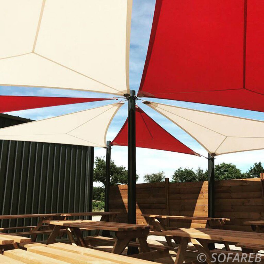 Voiles dombrage triangulaires design rouges et blanches au dessus de la terrasse en bois dun restaurant en Vendée