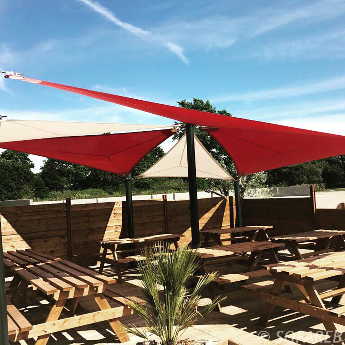 Voiles dombrage triangulaires rouges et blanches réalisées sur-mesure par Sofareb et installées au dessus de la terrasse dun restaurant