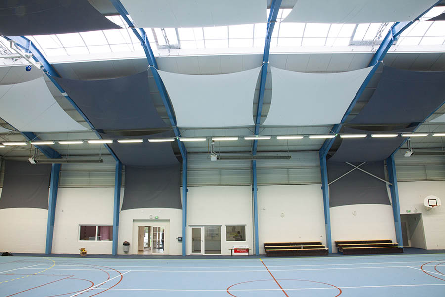 Toiles anti-bruit accrochées au plafond et aux murs d'une salle multisports