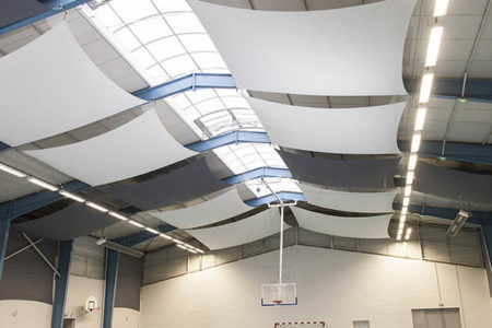 Toiles acoustiques blanches et grises accrochées au plafond d'une salle multisport