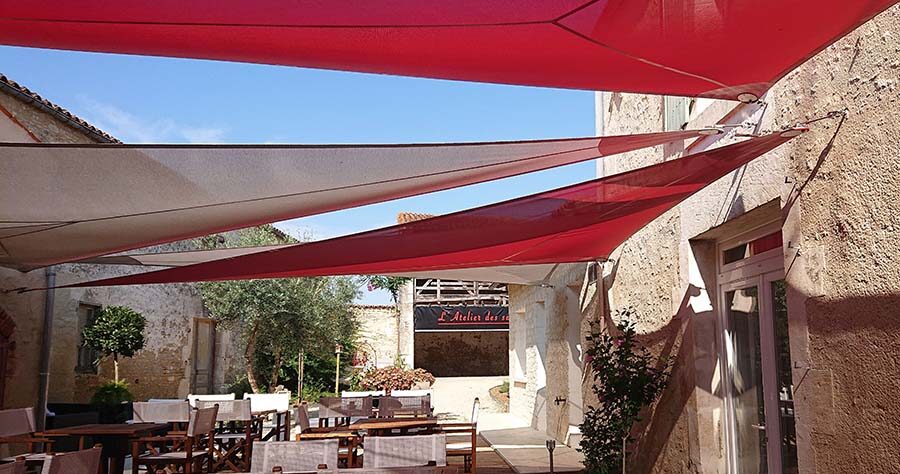 Voiles d'ombrage en triangles rouges pour la terrasse d'un restaurant