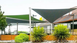 Voiles d'ombrage vertes et grises au-dessus d'une terrasse de Mac Donald